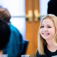 A student smiling while sitting at a table.